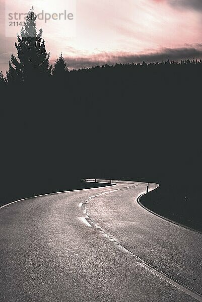 Kurvenreiche Straße bei Sonnenaufgang und Waldsilhouette. Leere Straße im Nationalpark Schwarzwald  Deutschland  Europa