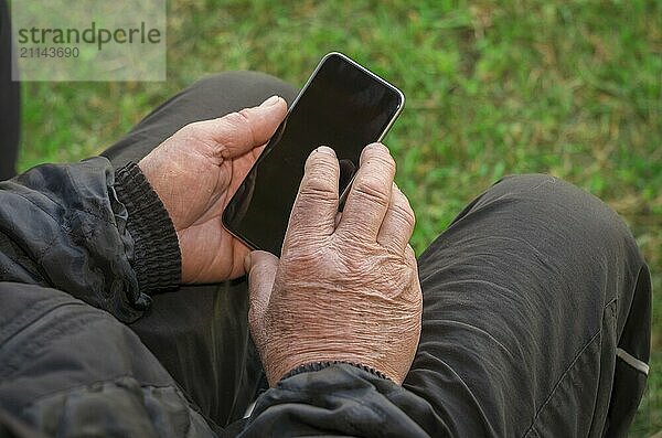 Nahaufnahme des faltigen Fingers eines Mannes  der ein Mobiltelefon berührt