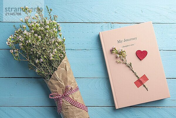 Rosa Notizbuch und schöne Frühlingsblumen Bouquet auf einem blauen Holztisch. Romantisch flach legen Bild