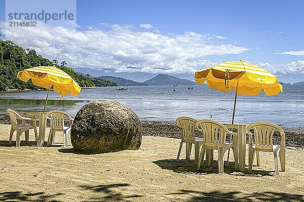 Strand mit Tisch  Stühlen  gelben Sonnenschirmen  Granitfelsen und herrlichem Meerblick  Paraty  Brasilien  Südamerika