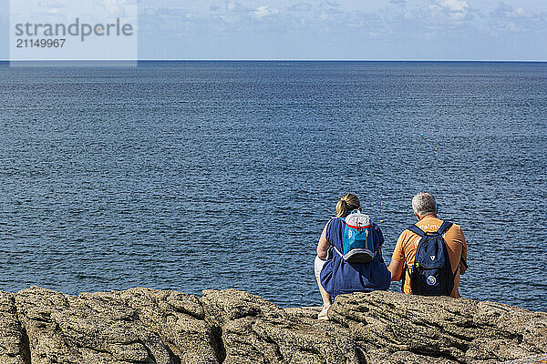 France  ile d'Yeu  85  Pointe des Corbeaux  hikers sitting on the rocks of the Cote sauvage  08/2023.