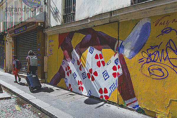 France  Paris. Street art and a family with a suitcase on a dirty street