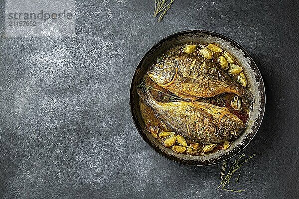 Food  Food  Baked sea bream or dorada with onion and herbs in pan on dark background