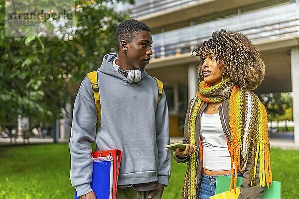 Two young and multiracial students chatting in the university campus