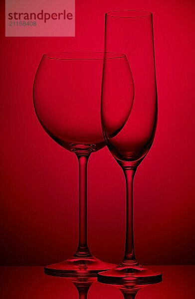 Two empty wineglasses on a red background