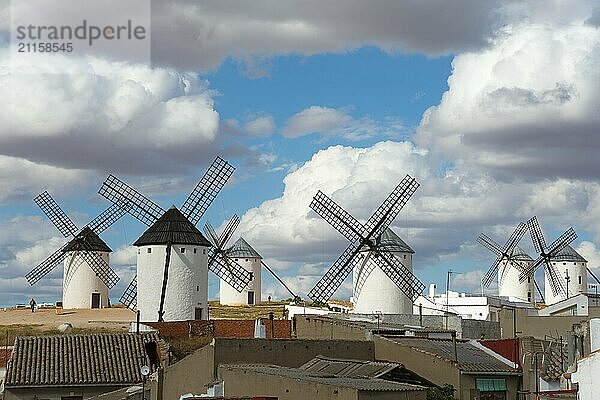 Several mills in a rural area  with old buildings in the foreground and a cloudy sky above  Campo de Criptana  Ciudad Real province  Castilla-La Mancha  Route of Don Quixote  Spain  Europe