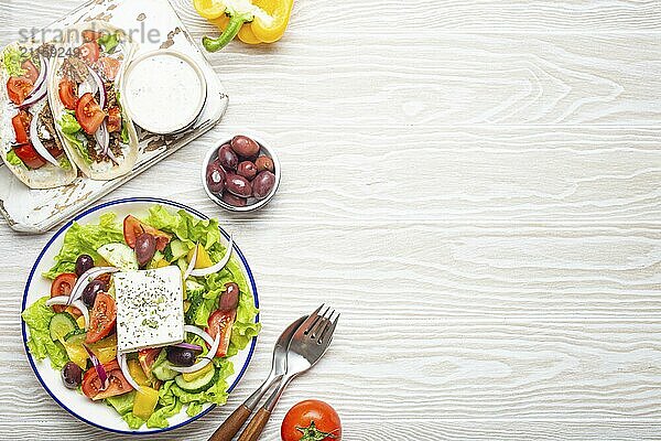 Traditionelles griechisches Essen: Griechischer Salat  Gyros mit Fleisch und Gemüse  Tzatziki Sauce  Oliven auf weißem rustikalen Holztisch Hintergrund von oben. Griechische Küche. Kopierraum  Lebensmittel Fotografie