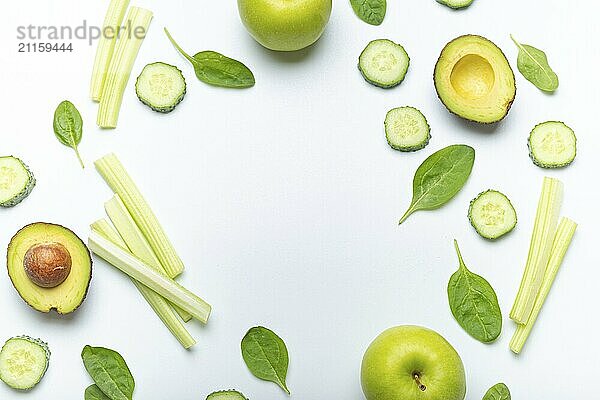 Flasche grüner Smoothie umgeben von grünem Obst und Gemüse: Äpfel  Avocado  Spinat  Selleriestangen  Gurke auf weißem einfachen Hintergrund von oben. Diät  gesunde Ernährung  Entgiftung Konzept  Lebensmittel Fotografie