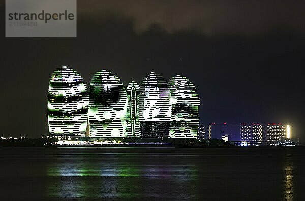 Nächtliche Ansicht von Gebäuden auf der Insel Phönix mit Gegenlicht und Reflexion im Meer in Sanya  Hainan  China  Asien