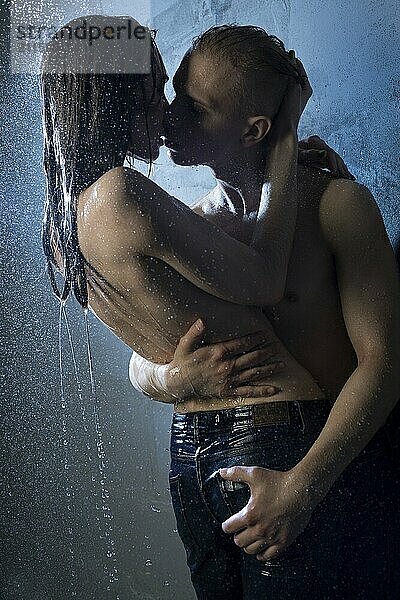 Girl wearing only jeans kissing with a nude man in a shower in the dark