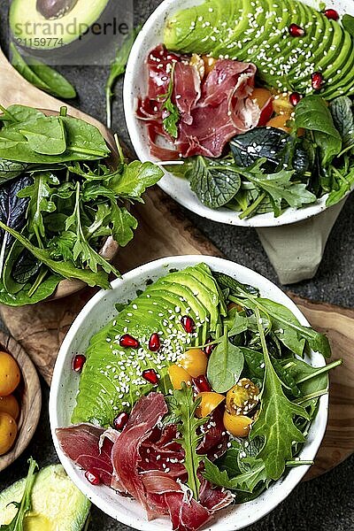 Food  Food  Low carbs bowl. Fresh salad with green spinach  rucola  avocado an ham serrano in white bowl  gray background  top view