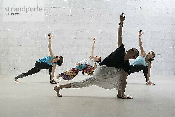 Group of people doing yoga exercises view against white brick wall