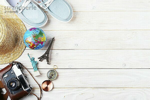 Travel planning simple background of compass  film camera  straw hat  moccasins  globe and souvenirs on white planks flat lay with copy-space