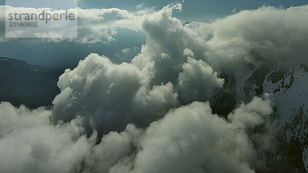 Fliegen durch schöne weiße flauschige Wolken zwischen hohen felsigen Bergen. Dolomiten Alpen Berge  Italien  Europa