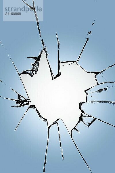 Pieces of broken glass with a hole in the center on a blue background. Texture of cracks on the window. Destruction effect for design