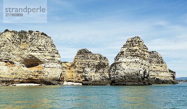 Atemberaubende Felsformationen an der Küste von Lagos in Portugal erheben sich majestätisch aus dem klaren türkisfarbenen Wasser unter einem strahlend blauen Himmel und verkörpern die Schönheit und Ruhe einer unberührten Naturlandschaft