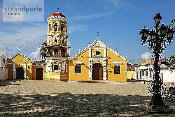 View to beautiful historic Church Santa Barbara (Iglesia de Santa Barbara) and square (plaza) partly in shadow  Santa Cruz de Mompox  sunlight and blue sky  World Heritage