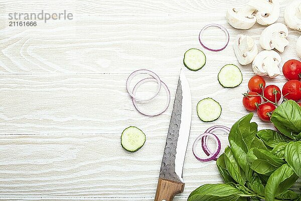 Lebensmittel Kochen Hintergrund: frische Zutaten mit Küchenmesser  Basilikum  Kirschtomaten  Pilze  schneiden Gurken und Zwiebeln auf weißem Holz Hintergrund von oben gesehen. Mahlzeit Vorbereitung Vorlage  Platz für Text  Lebensmittel Fotografie  food photography