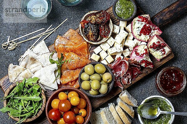 Food  Food  Antipasto. Wine set appetizer. Ham serrano  smoked salmon  dried and fresh tomatoes olive cheese  wine on board. Top view  gray cncrete background