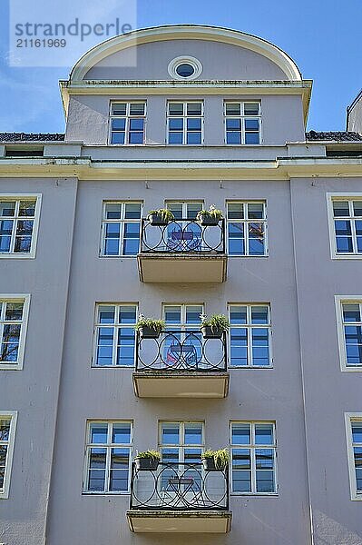 Residential building with several balconies and windows  pink facade  plants on the balconies  clear blue sky  Bergen  Vestland  Norway  Europe