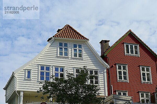 Two wooden houses  one with a white and one with a red wooden facade  under a sky with clouds  Bergen  Vestland  Norway  Europe