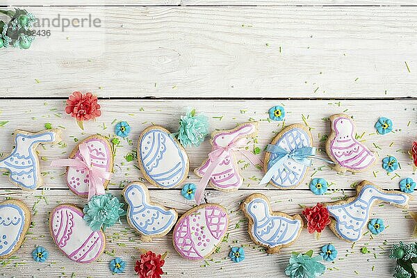 Easter frosted cookies in shape of egg chicken and rabbit on white wooden table background along with sugar sprinkles. Flat lay horizontal mockup