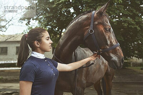 A young girl talking and takes care of her horse. She loves the animals and joyfully spends her time in their environment