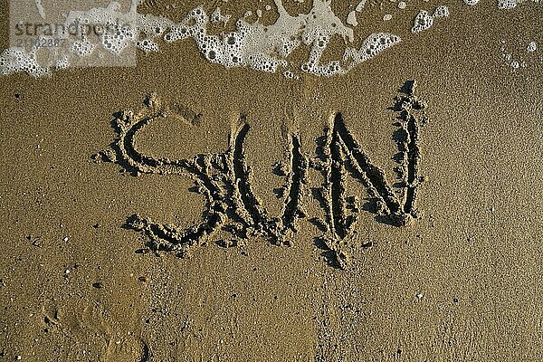 Turkish sea shore with word sun written on the sand washed by waves high angle close up view