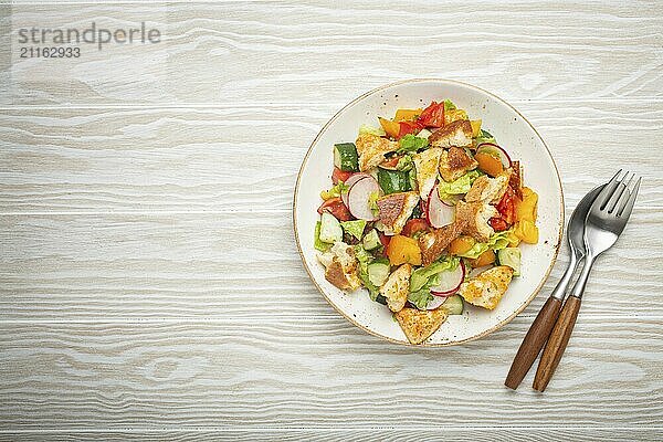 Traditionelle Levante Gericht Fattoush Salat  arabische Küche  mit Fladenbrot Croutons  Gemüse  Kräuter. Gesunder vegetarischer Salat aus dem Nahen Osten  rustikaler hölzerner weißer Hintergrund von oben  Platz für Text  Food Fotografie