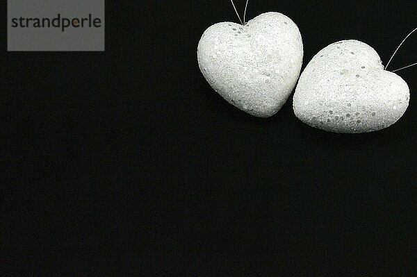 Two white hearts on a black background on top left