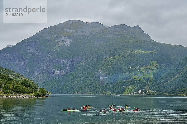 Several kayakers in a fjord surrounded by forested mountains and clouds  Geiranger  Geiranger Fjord  Stranda  Romsdal  Norway  Europe