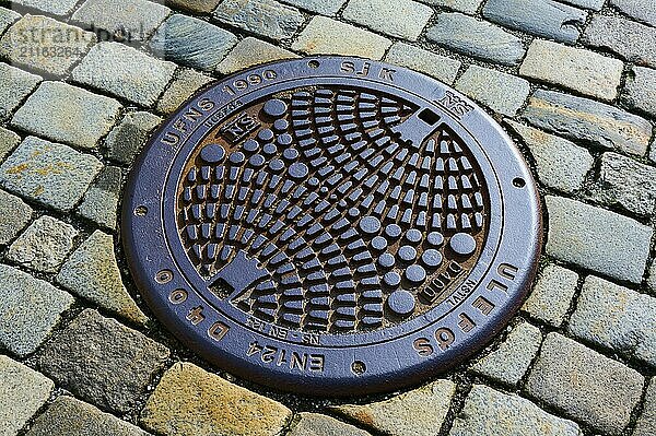 Round manhole cover with geometric pattern on cobblestones  Bergen  Vestland  Norway  Europe