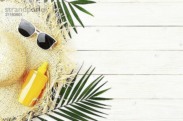 Vacation travel planning simple background of straw hat sunglasses palm leaves and sunblock lotion on white planks flat lay with copy-space