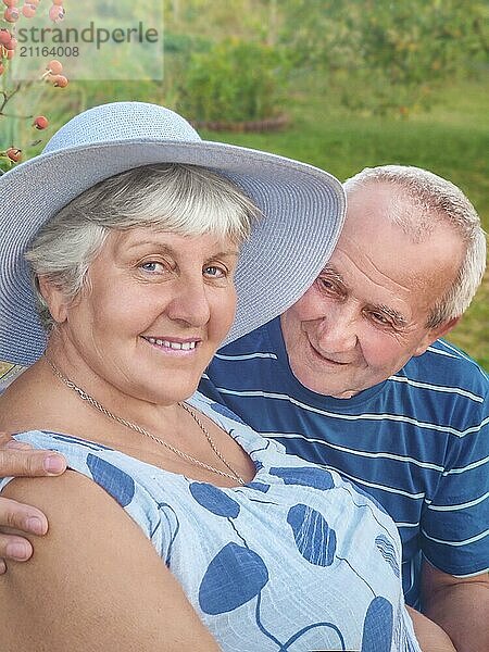 Authentic outdoor shot of aging couple having fun in the garden and blessed with love. During their game man is trying to kiss his partner and she is laughing out loud. Love and family