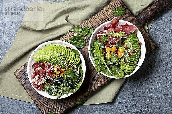 Food  Food  Low carbs bowl. Fresh salad with green spinach  rucola  avocado an ham serrano in white bowl  gray background  top view