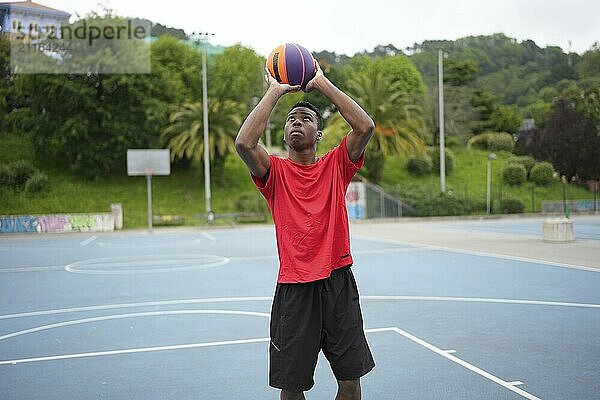 Concentrated african american basketball player about to throw the ball in an outdoor court