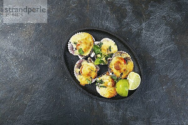 Food  Baked seafood shellfish scallops with cheese and lemon. black background