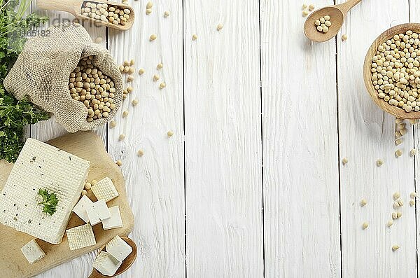 Soy Bean curd tofu on cutting board and in hemp sack on white wooden kitchen table. Space for text