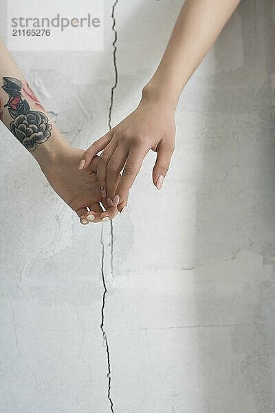 Female holding hands cropped shot against cracked wall