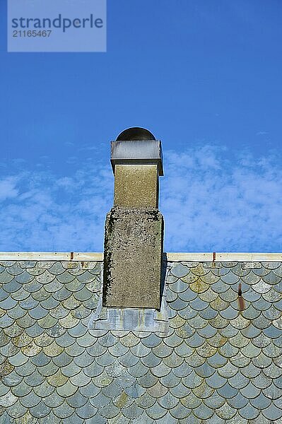 A stone chimney on a shingle-covered roof against a clear blue sky  Bergen  Vestland  Norway  Europe