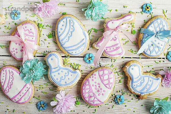 Easter frosted cookies in shape of egg chicken and rabbit on white wooden table background along with sugar sprinkles. Flat lay horizontal mockup