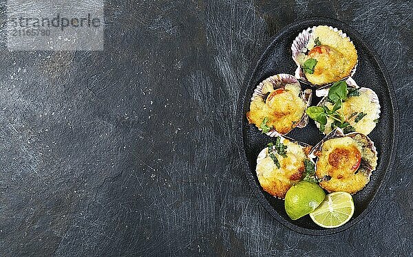 Food  Baked seafood shellfish scallops with cheese and lemon. black background