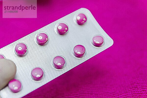 Pink pills in a blister on a pink background