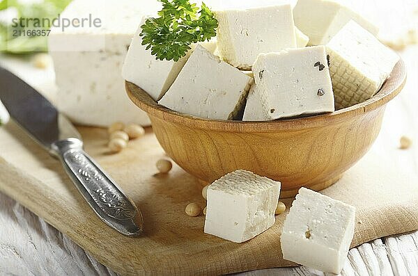 Soy Bean curd tofu in wooden bowl on white wooden kitchen table. Non-dairy alternative substitute for cheese. Place for text