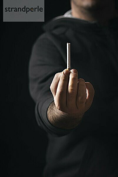 Man giving away the cigarette concept. Quit smoking concept. Stop smoking effort. Black background. Low light with copy space