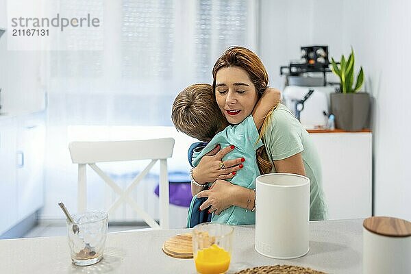 Happy moment of a caucasian school boy embracing her mother while eating breakfast at home