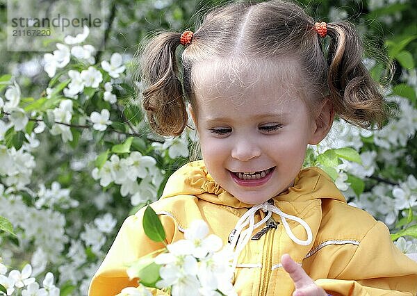 Happy little girl near blossoming apple tree at spring