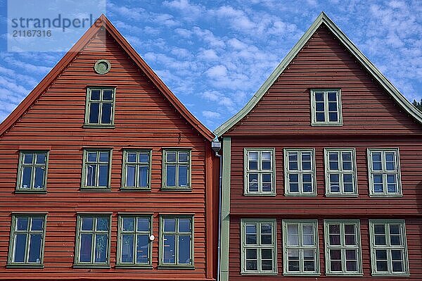 Traditional red wooden houses under a blue sky with pitched roofs and multiple windows in a sunny old town  Bryggen  Bergen  Vestland  Norway  Europe