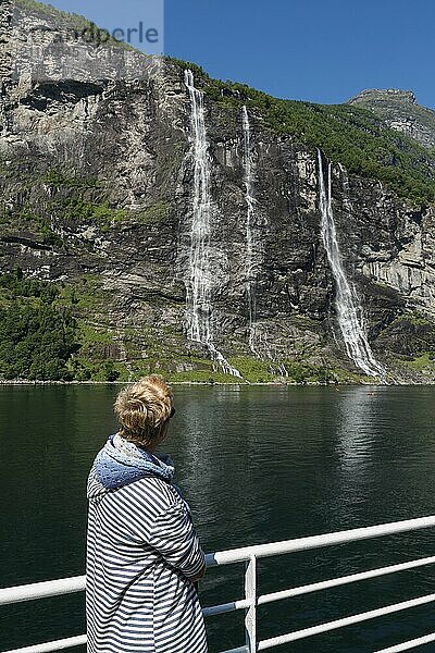 Woman on a ferry boat looking at the waterfall at the geiranger fjord in norway