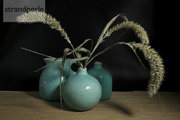 Three blue vases still life on wooden table with wheat or corn it in on black background